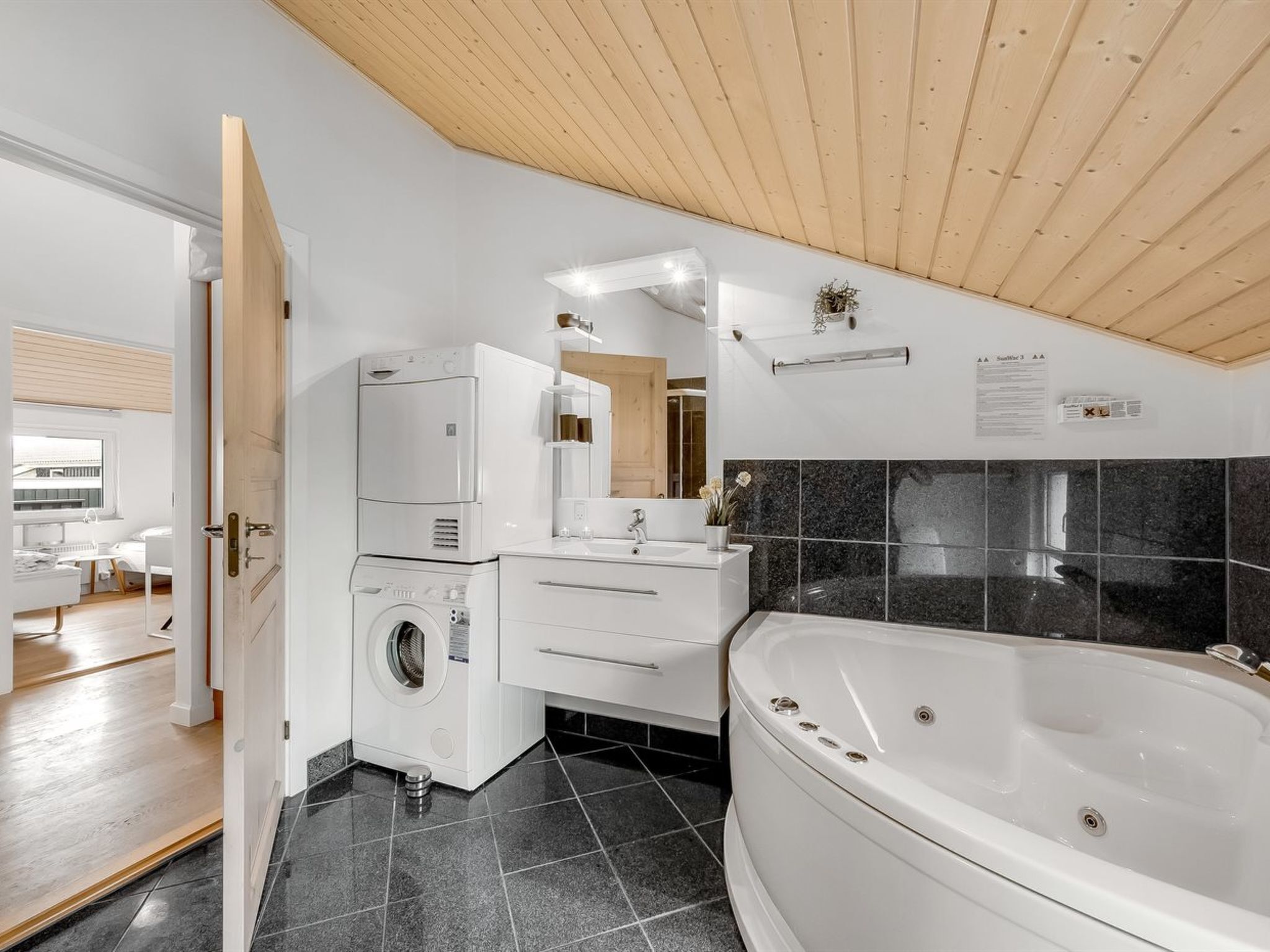 A modern bathroom with a washing machine, a sink, and a bathtub.