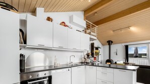 A modern kitchen with white cabinetry, a built-in oven, a black countertop, and a wooden ceiling. - "Samuil" - 300m to the fjord by Interhome (Vinderup)