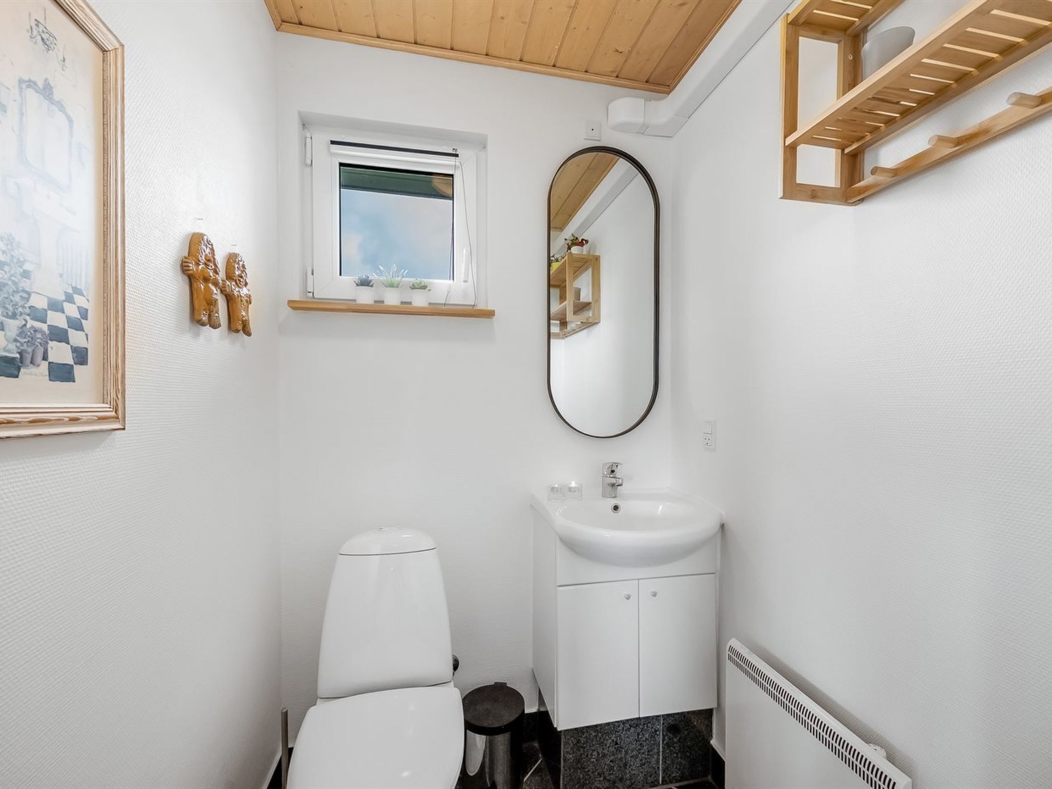 A compact bathroom with a toilet, sink, and a small window.