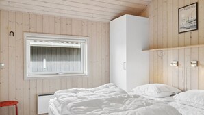 Une chambre à coucher avec un lit, une fenêtre, un radiateur, une armoire et une petite table.
