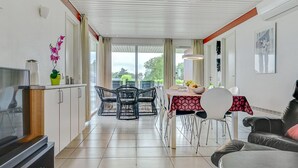 Una cocina moderna con comedor, que incluye un televisor, armarios y una mesa de comedor con sillas.