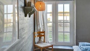 A room with a large window, a wooden chair, a hanging lamp, and a bed with blue bedding. - "Answald" - 250m from the sea by Interhome (Harboøre)