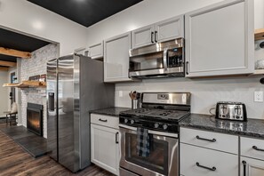 A modern kitchen with stainless steel appliances, white cabinetry, and a built-in fireplace. - Graphite MTN Retreat - .75 mi to Hague Beach, access to Hague Brook, EV charger (Hague)