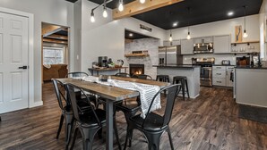 Una cocina moderna con una isla central, electrodomésticos integrados y un comedor con mesa y sillas de madera.