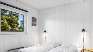 Ein Schlafzimmer mit zwei Einzelbetten, einem Fenster mit Blick auf Bäume und zwei Wandlampen.