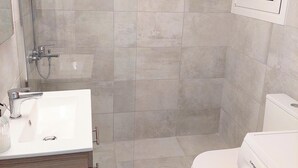 A bathroom with a shower, toilet, sink, and washing machine. - Modern Apartment in Acropolis Museum (Athens)