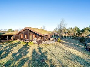 Eine Blockhütte mit einem Strohdach, einer Veranda und einer kleinen Terrasse.