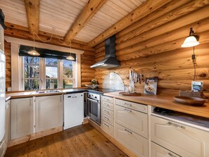 Eine Küche mit Holzwänden, einem Herd, einem Geschirrspüler und einem Fenster mit Blick auf Bäume.