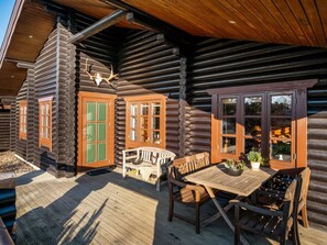 Eine Blockhütte mit Veranda, Holzmöbeln und einer Dekoration aus einem Hirschschädel.