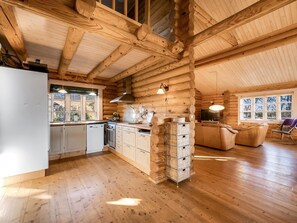 A log cabin interior with a kitchen, dining area, and a fireplace.