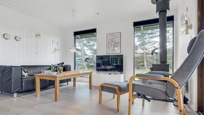 A modern living room with a sofa, a wooden table, a grey armchair, and a TV. - "Aileen" - 900m from the sea by Interhome (Væggerløse)
