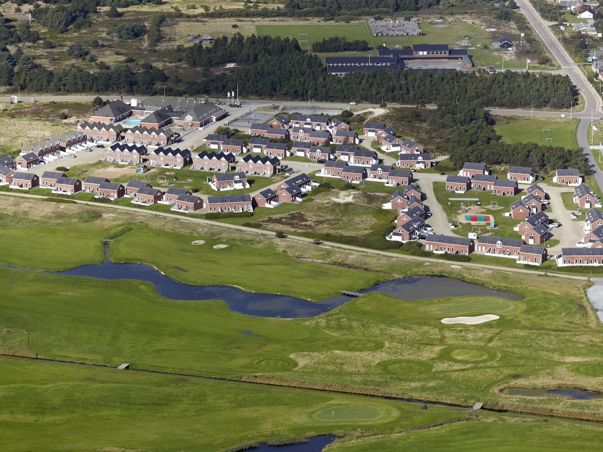 Vista aérea de una zona residencial con casas, un campo de golf y un estacionamiento.