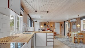 A modern kitchen with a wooden island, white cabinetry, and a large window providing natural light. - "Winona" - 300m from the sea by Interhome (Væggerløse)