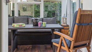 A cozy outdoor seating area with wicker furniture, a table with a mug and a box, and a view of a house with a tiled roof. - "Winona" - 300m from the sea by Interhome (Væggerløse)