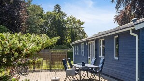 A patio with a table and chairs, a bicycle, and a house with a dark exterior. - "Winona" - 300m from the sea by Interhome (Væggerløse)