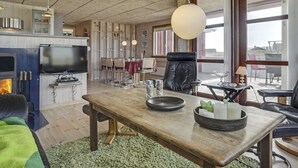 Een moderne woonkamer met een houten eettafel, leren fauteuils, een televisie en een open haard.