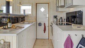 Een moderne keuken met witte kasten, een centraal eiland, roestvrijstalen apparatuur en hanglampen.
