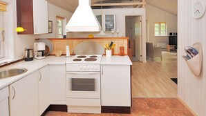 Une cuisine compacte dotée d’un îlot central, d’un four encastré et d’un luminaire suspendu.