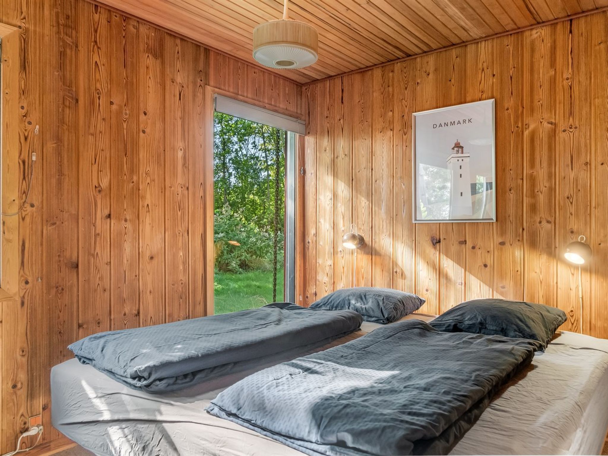 A wooden room with two beds, a door leading outside, and a framed picture on the wall.