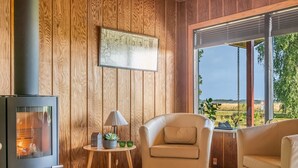 A cozy room with a wood-paneled wall, a fireplace, a comfortable chair, and a view of the outdoors. - "Tayana" - 75m to the fjord by Interhome (Storvorde)