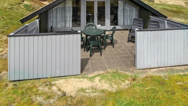A small, single-story building with a sloped roof, a sign reading "SIRT", and a patio area with a table and chairs. - "Keijo" - 1.5km from the sea by Interhome (Fanø)
