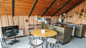 A cozy kitchen with wooden walls, a round dining table, and a built-in stove. - "Keijo" - 1.5km from the sea by Interhome (Fanø)
