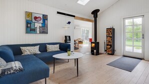 Un salón espacioso con un sofá azul, una mesa de centro redonda, chimenea y un ventanal grande.