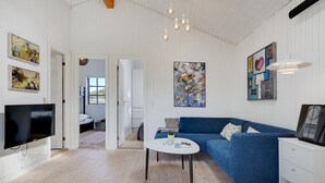 Una sala de estar moderna con un sofá azul, una mesa de centro blanca y un televisor de pantalla plana.