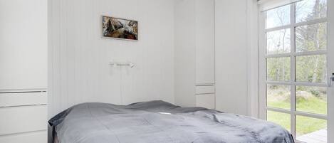 A bedroom with a bed, a door to an outdoor area, and a painting on the wall.