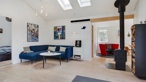Una sala de estar moderna con un sofá azul, una mesa de centro redonda y un estufa de leña negra.