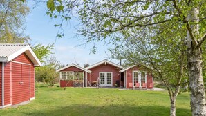 Una casa de madera roja con un porche delantero y un pequeño jardín.