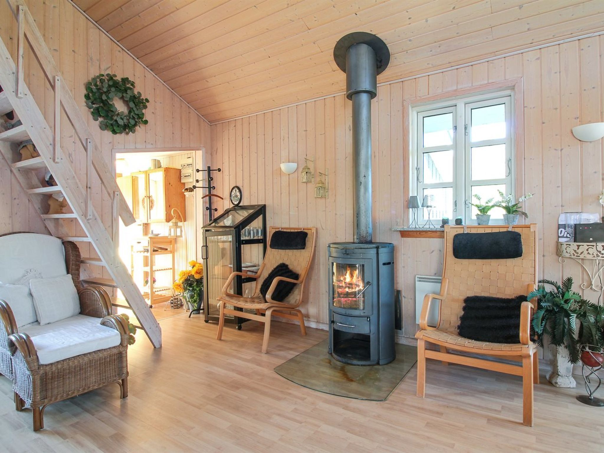 L’intérieur chaleureux d’un chalet, avec un décor en bois, une cheminée, des meubles en osier et un escalier.