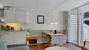 Un espacio habitable compacto con kitchenette, zona de comedor y sala de estar con sofá y mesa.