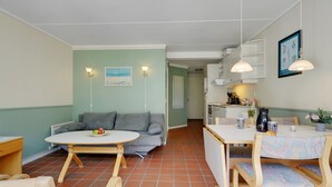 Un espacio habitable compacto con comedor, kitchenette y sofá.