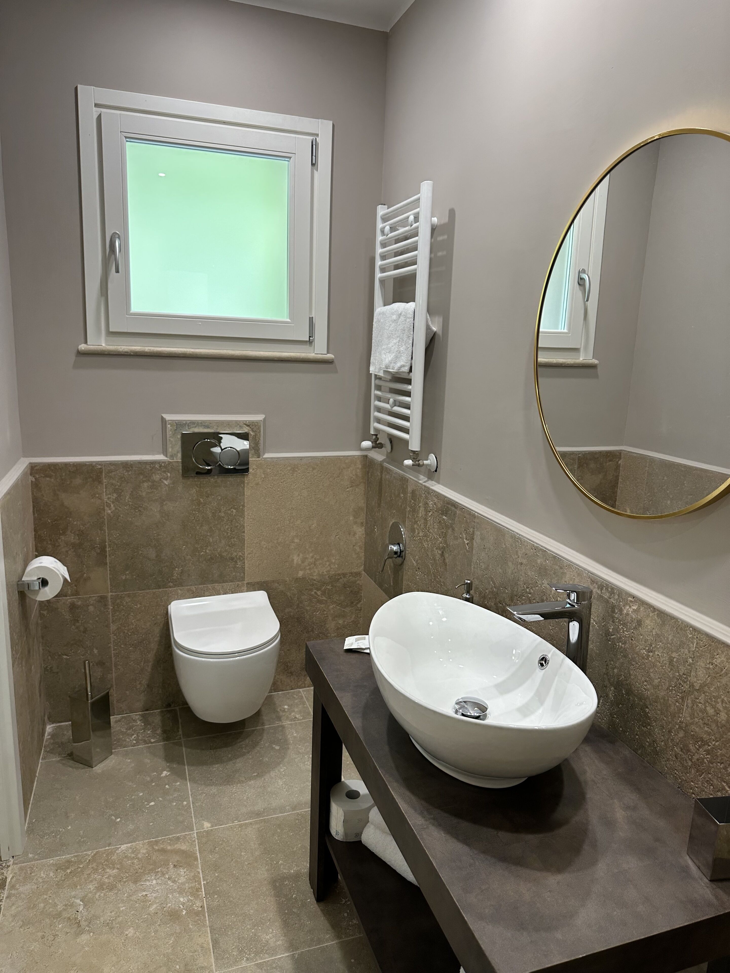 Un baño moderno con inodoro, lavamanos y toallero.