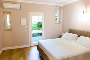 A bedroom with a bed, a door leading to a balcony, and an air conditioning unit. - La Tenuta di Rocca Bruna Country Resort (Tivoli)