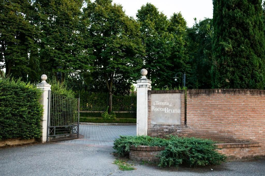 A gated entrance with a sign reading "4 Tenuta di RoccaBruna".