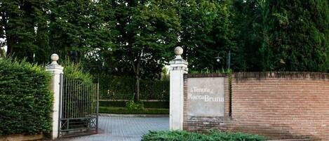 A gated entrance with a sign reading "4 Tenuta di RoccaBruna".