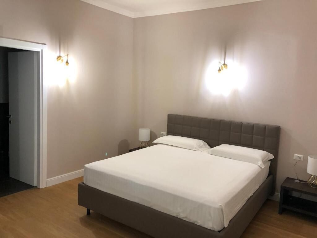 Un dormitorio con una cama grande, dos mesitas de noche y lámparas de pared.