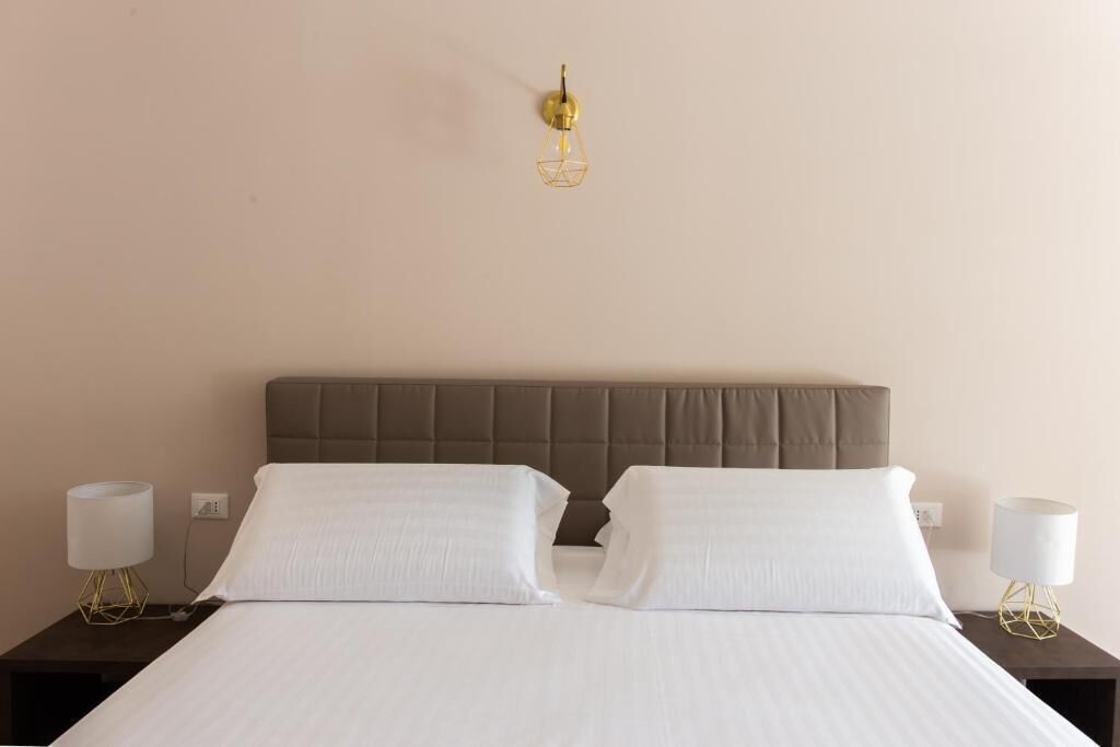 A hotel room with a bed, two nightstands, and a wall-mounted light fixture.