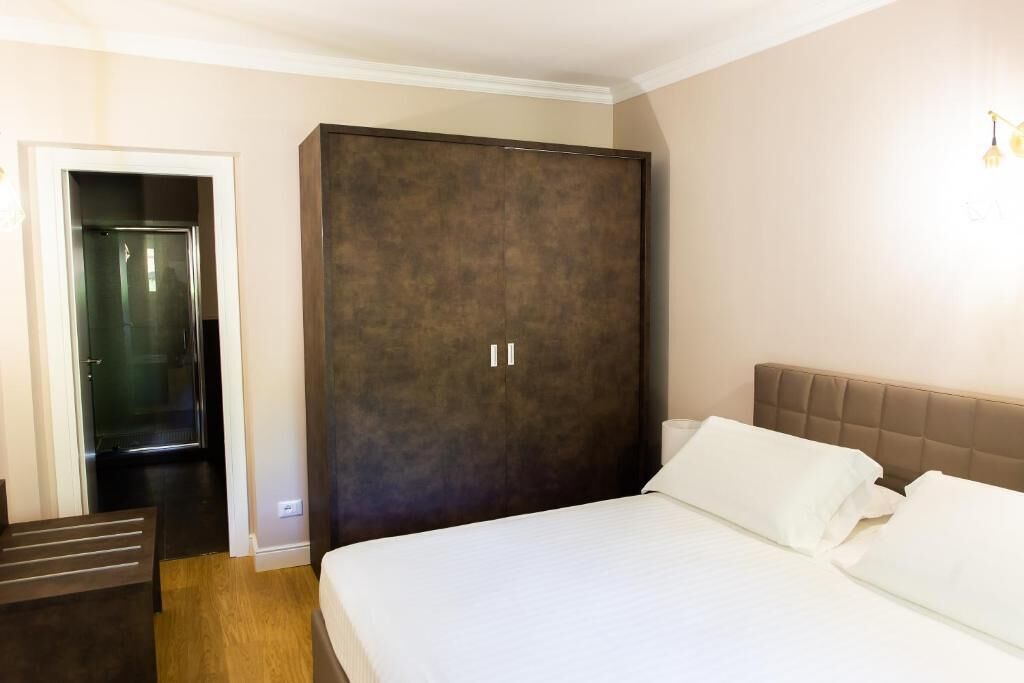 A hotel room with a large bed, a wardrobe, and a door leading to a bathroom.