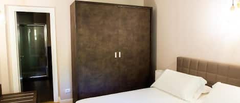 Una habitación de hotel con una cama grande, un armario y una puerta que da a un baño.