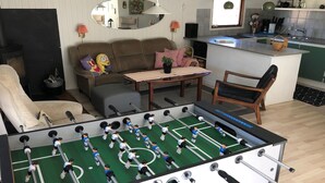 A living room with a foosball table, a sofa, a coffee table, and a kitchen area in the background. - "Harald" - 300m from the sea by Interhome (Idestrup)