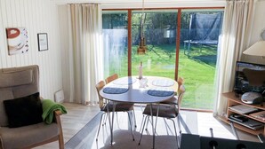 A cozy room with a dining table, chairs, a sofa, a TV, and a large sliding glass door leading to a garden. - "Harald" - 300m from the sea by Interhome (Idestrup)