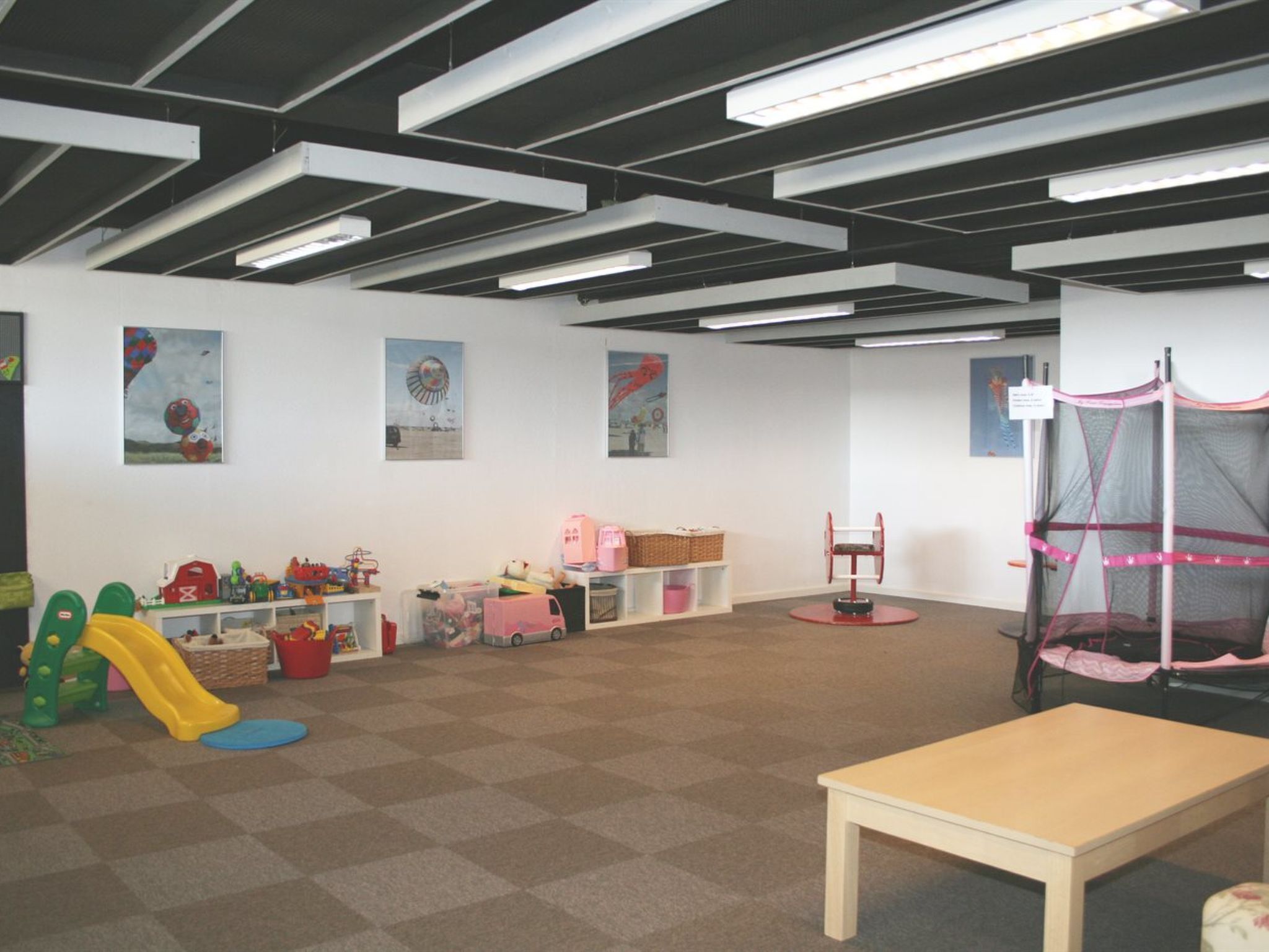 Ein Spielzimmer mit Rutsche, Spieltischen und Spielzeug.