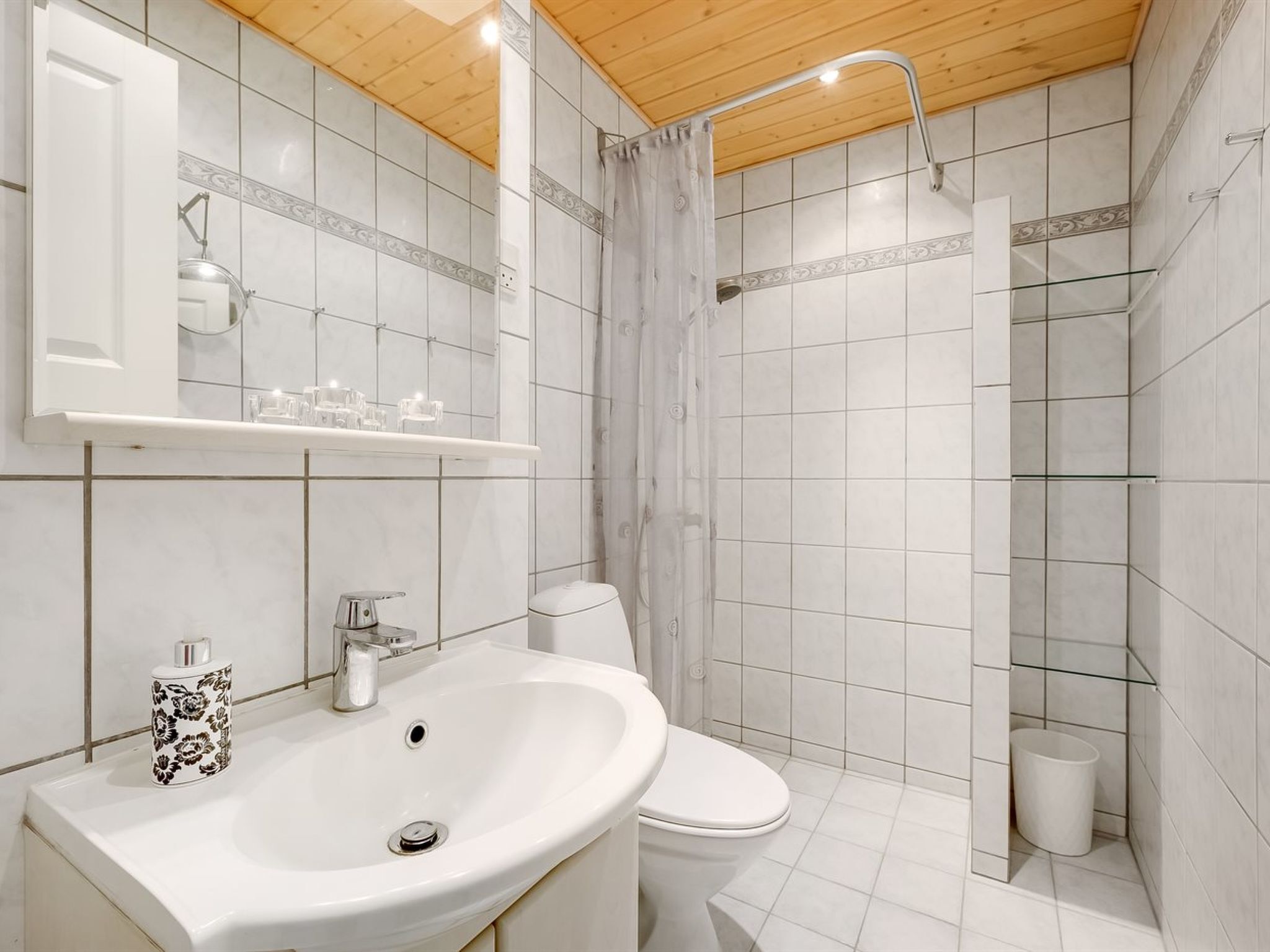 Et moderne badeværelse med en hvid vask, toilet og bruseområde.