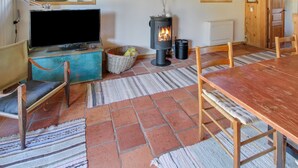 A cozy room with a television, a fireplace, a dining table, and chairs.