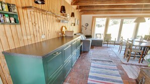 A kitchen with wooden cabinets, a striped rug, and a dining area with a table and chairs.