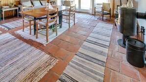 A rustic interior with a wooden dining table, chairs, a sofa, and a stone-tiled floor.