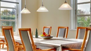 A dining area with a table set for six, surrounded by wooden chairs with cushioned seats. There are three pendant lights hanging above the table. - "Swaver" - 300m to the fjord by Interhome (Storvorde)
